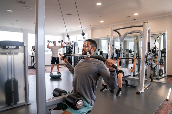 People are working out in a gym, using various machines and equipment for their exercises.