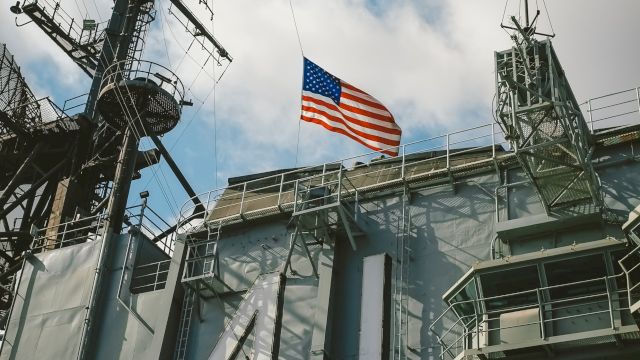 The image shows a large naval ship with the number 41 painted on its side and an American flag waving above. The sky above has scattered clouds.