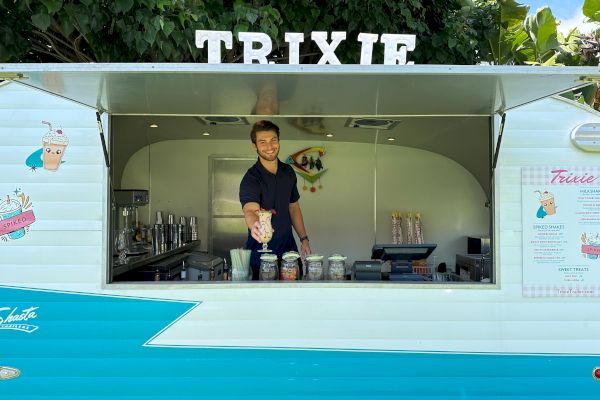 A person stands inside a teal and white food truck named 