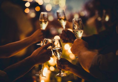 People raising champagne glasses in a toast, surrounded by warm, blurred lights and an elegant, celebratory atmosphere.