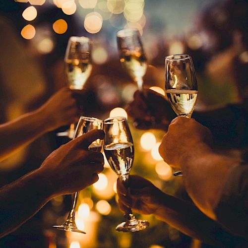 People raising champagne glasses in a toast, surrounded by warm, blurred lights and an elegant, celebratory atmosphere.