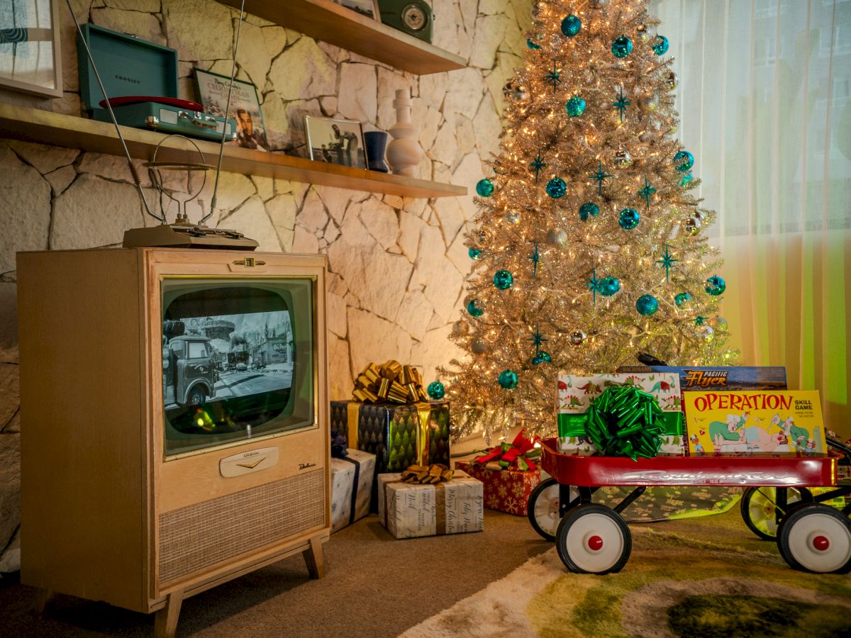 A vintage Christmas scene with a decorated tree, gifts, a wagon with toys, and an old television showing a black and white image.